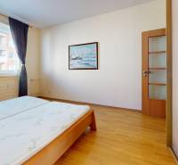 A bedroom with a wood-decor floor in a 3-room apartment, with a painting hanging on the wall.