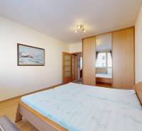 A bedroom with a double bed, a mirrored wardrobe, and a wooden decor floor in a 3-room apartment.