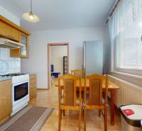 A kitchen in a 3-room apartment with wooden decor and a dining table by the window.
