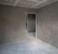A room in a 3-room apartment with gray walls and ceiling. Bare floors.