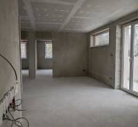 Unfinished space of a 3-room apartment with unplastered walls and large windows.