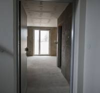 Interior of a 3-room apartment with a concrete floor and a large French window.