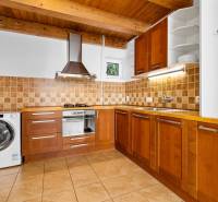 A kitchen in a family house with wooden decor, ceramic tiles, and built-in appliances.