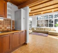 A kitchen with tiles and a wooden cabinet connected to the living room in a family house.