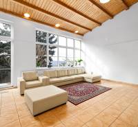 Living room in a family house with a cream sofa, large windows, and ceramic tiles.