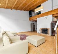 Living room in a family house with a fireplace, white sofa, and wooden ceiling.