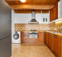A kitchen in a family house with wooden cabinets, a floor with a wooden decor, appliances.