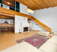 Living room with a fireplace and kitchen, wooden decor flooring, stairs to the attic.