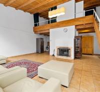 Living room with a fireplace, leather sofa, stone tiles, and wooden ceiling in a family house.