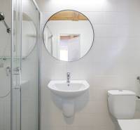 Bathroom with a round mirror, shower, and sink in a family house.