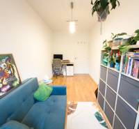 A room in a 4-room apartment with a sofa, a bookshelf, and a wooden decor floor.