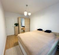 Bedroom in a 4-room apartment with a spacious bed, wardrobe, and wooden decor flooring.