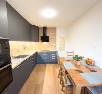 A kitchen in a 4-room apartment with a wooden decor floor and modern furniture.
