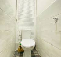 Bathroom in a 3-room apartment, white toilet, tiles, blind, shelf for products.
