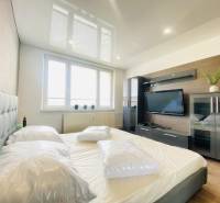 A bedroom in a 3-room apartment with an upholstered bed, a television, and a wooden decor floor.