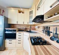 A kitchen in a 3-room apartment with stainless steel appliances and a wood-patterned floor.