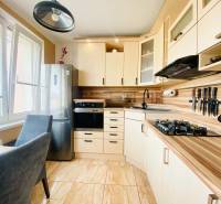 A kitchen in a 3-room apartment furnished with light-colored furniture and a dining table.
