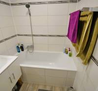 A bathroom in a 2-room apartment with a shower, bathtub, and a floor with a wooden decor.