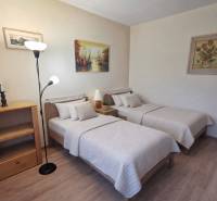Double bedroom with wood-patterned flooring in a two-room apartment, cozy beds.