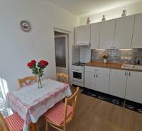 A kitchen in a 2-room apartment with white cabinets and a table with red details.