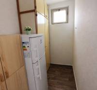 A narrow space in a 2-room apartment with a wardrobe, a freezer, and a wooden decor floor.