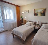 Double bedroom in a 2-room apartment with a balcony and a wooden decor floor.
