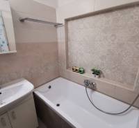 A bathroom in a 2-room apartment with a bathtub and decorative tiles.