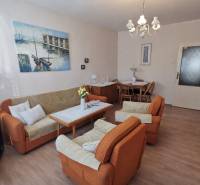 Living room in a two-room apartment with a wooden decor floor and orange furniture.