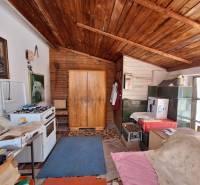 A room in a family house with a wooden ceiling, a tiled stove, and a gas stove.