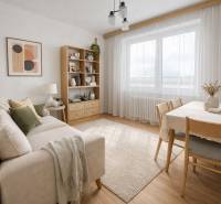 Living room in a family house with a wooden decor floor, a comfortable sofa, and a dining table.