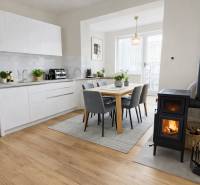A kitchen in a family house with a fireplace, a wooden decor floor, and a dining table.
