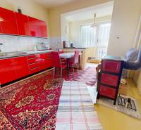A kitchen with a red cabinet, carpet, and fireplace in a family house.