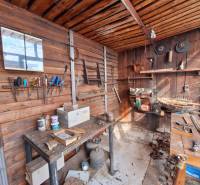 Workshop in a family house with wooden walls, workbenches, and tools.
