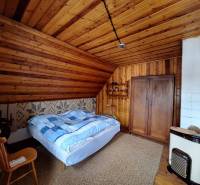 Bedroom in a family house with wooden paneling, a bed, and a cabinet.