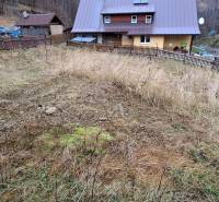 A plot of land for residential use in Oščadnica with a sloping terrain and neighboring houses in the background.