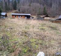 A plot for residential use in Oščadnica, with a wooden house and a forest backdrop.