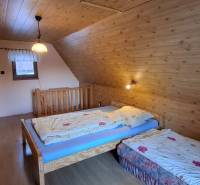 A room in a cabin with wooden decor, two beds, and a window, ideal for relaxation.