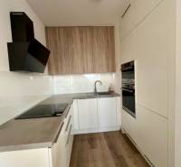 A kitchen in a 2-room apartment with a wooden decor floor and built-in appliances.