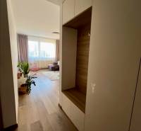 A hallway in a 2-room apartment with a wooden decor floor and light furniture.