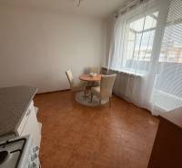 A kitchen in a 3-room apartment with a ceramic floor, table, chairs, and a large window.