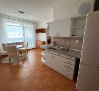 A kitchen in a 3-room apartment with a dining area and a wooden-patterned floor.