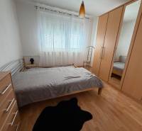A bedroom in a 3-room apartment with a wooden decor floor and a built-in wardrobe.
