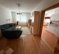 Living room in a three-room apartment with a wooden decor floor, connected to the kitchen.