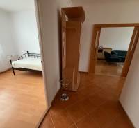 A hallway leading to the rooms in a 3-bedroom apartment with a wooden decor floor.