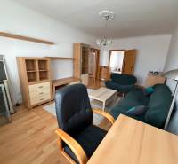 Living room in a three-room apartment with a wooden decor floor, furniture, and a sofa.