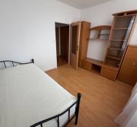 Single bed, wardrobe, and shelving unit in a 3-room apartment with a wooden decor floor.