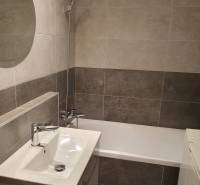 A bathroom in a 3-room apartment with a minimalist design, a bathtub, and a sink.