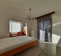 Bedroom in a 3-room apartment with a bed and a large window, wooden decor flooring.