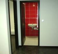 Interior of an office with white walls and red tiles behind the sink.