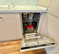 A kitchen in a 2-room apartment with a dishwasher and a wooden decor floor.